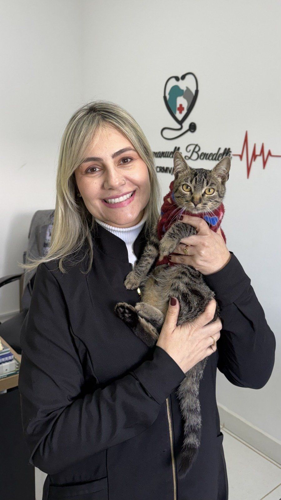 Médica veterinária do Le Petit segurando um gato tigrado de roupinha